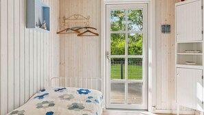 A bedroom with a bed, a wardrobe, a hanging rack, and a door leading to a balcony. - 4 Star Holiday Home in Hadsund (Hadsund)