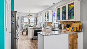 A modern kitchen with white cabinets, a granite countertop, and a built-in island. - Ocean Crystal A: 2nd-row duplex, ocean views, walk to beach/pier (Atlantic Beach)