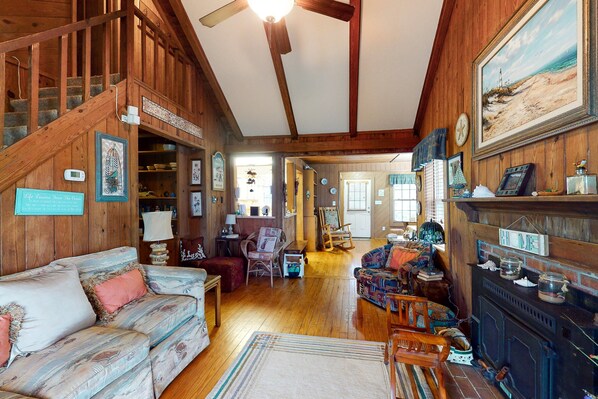 A wooden interior with a staircase, a sofa, a fireplace, and various decorations. - Beautiful Home in Oceanfront Location w/Vaulted Ceilings, Free WiFi, Deck, W/D (Atlantic Beach)