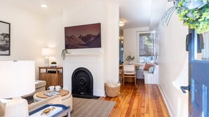 Una sala de estar con chimenea, un comedor con mesa y sillas, y vistas al exterior a través de una ventana.