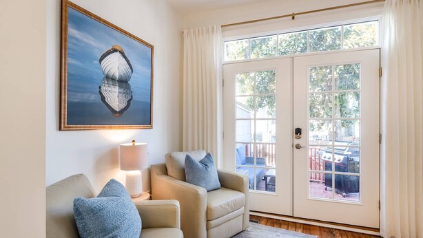 Un salón con dos sillones color beige, un tapete azul, una lámpara y un cuadro en la pared.