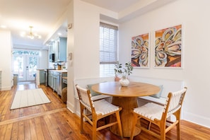 A dining area with a round wooden table, two chairs, and a vase with plants.