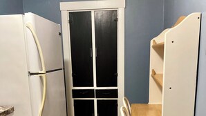 Una cocina compacta con un refrigerador blanco, una mesa de comedor de madera y un armario blanco.