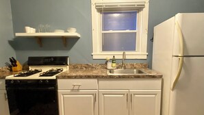 Una cocina con armarios blancos, estufa, fregadero y refrigerador.