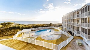 A beachfront hotel with a pool, multiple balconies, and a view of the ocean.