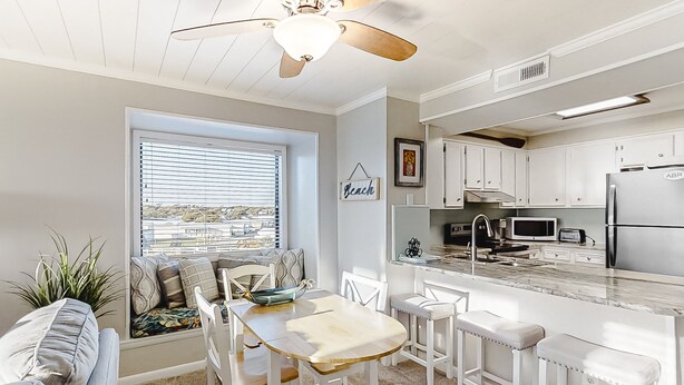 A modern kitchen with white cabinetry, a built-in island, and a view of the outdoors.