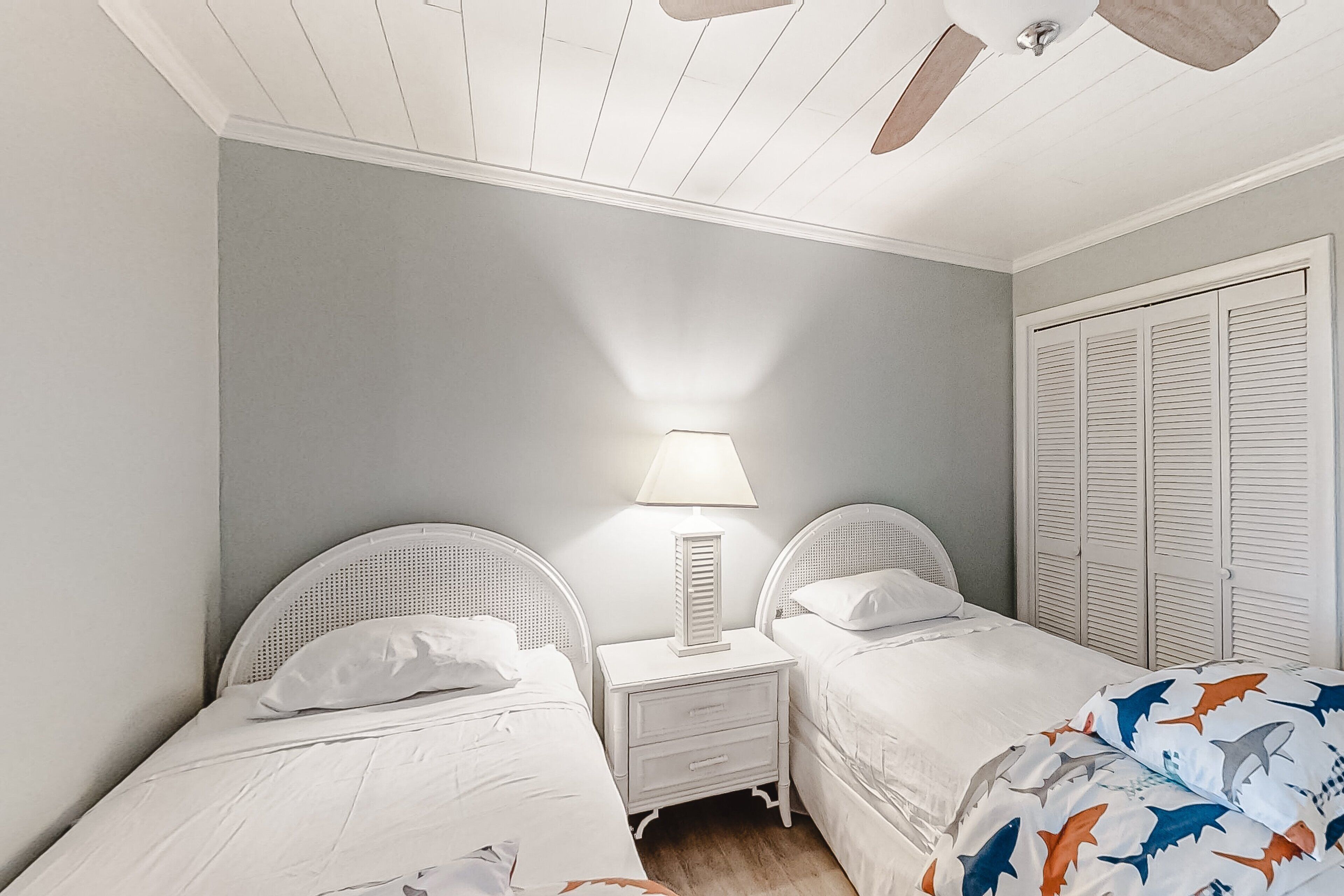 Een slaapkamer met twee bedden, een nachtkastje met lamp en een inloopkast met verstelbare deuren.