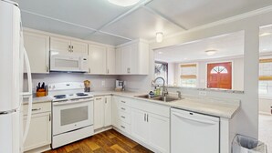 A kitchen with white cabinets, a microwave, stove, sink, and dishwasher.
