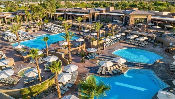 Un resort con varias piscinas, tumbonas y sombrillas.
