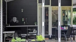 A covered outdoor area with a table and chairs, a grill, and potted plants. - 5 Star Holiday Home in Jaegerspris (Melby)