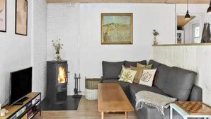 A cozy living room with a fireplace, a sofa, a coffee table, and a television. - 5 Star Holiday Home in Jaegerspris (Melby)