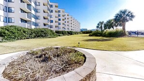 Un edificio de apartamentos moderno con varios balcones, un césped bien cuidado y un camino de piedra.