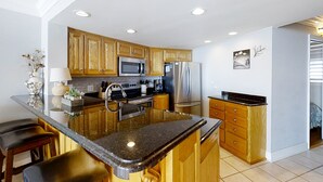 Una cocina moderna con armarios de madera, electrodomésticos de acero inoxidable y una isla central con taburetes de bar.