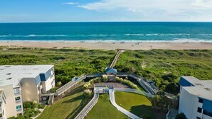 Ein Resort mit Blick auf den Strand, einem Poolbereich und einer Promenade, die zum Strand führt.
