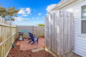 A backyard with a wooden fence, a patio area with a blue chair, and a small shed.