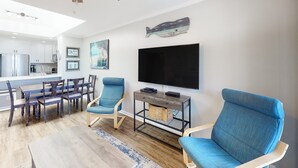 Una sala moderna con comedor, televisor montado en la pared y ventilador de techo.