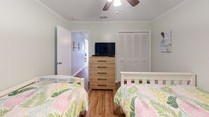Un dormitorio con dos camas, un aparador, un televisor y un ventilador de techo.
