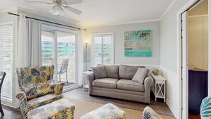 A living room with a sofa, armchair, and a ceiling fan. - First-Floor Condo with Balcony, WiFi & Shared Hot Tub, Pools, Tennis, Putt-Putt (Atlantic Beach)
