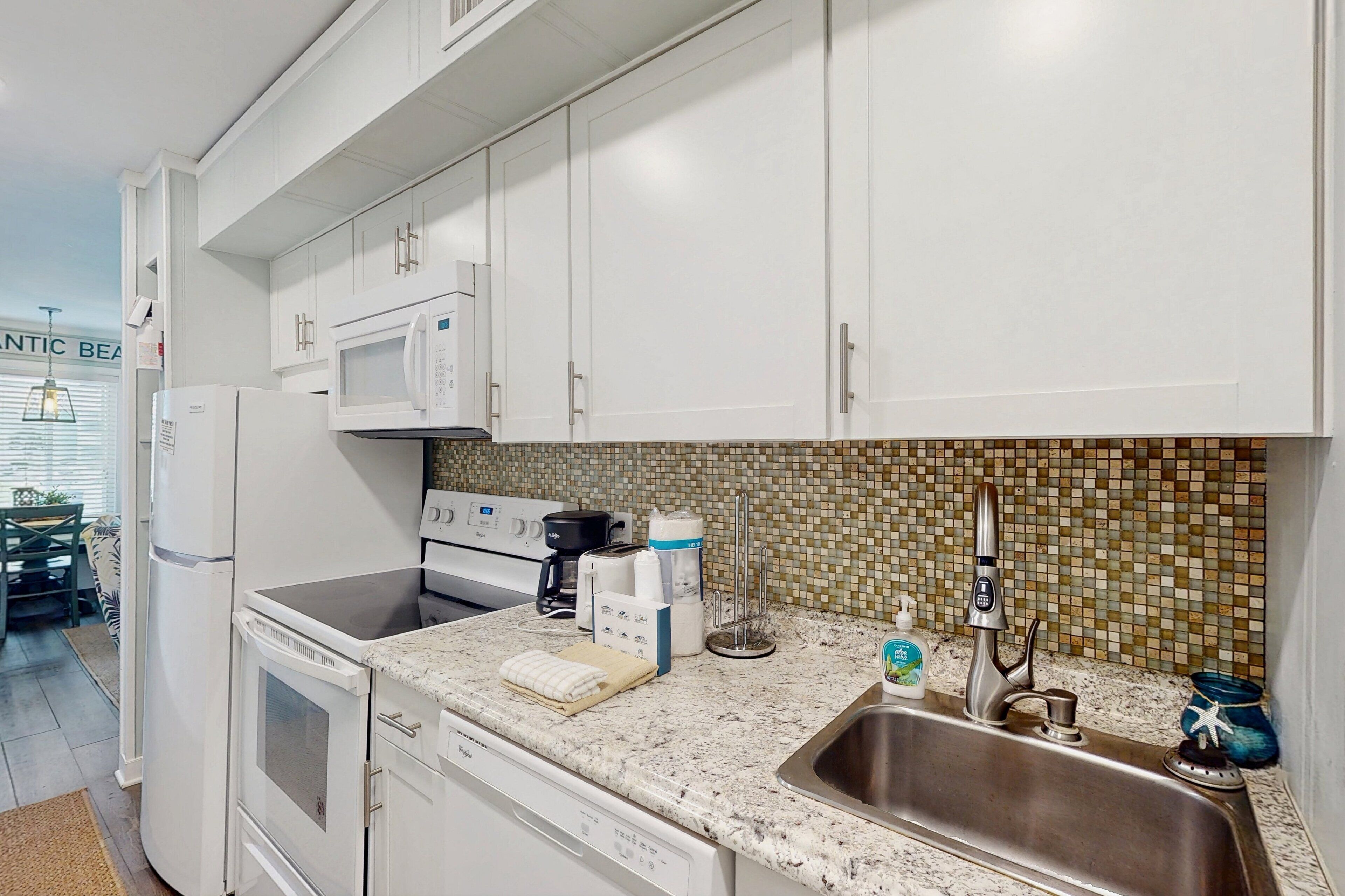A compact kitchen with white cabinets, a microwave, a coffee maker, and a dishwasher.