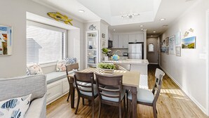 Een moderne keuken met witte kasten, een centraal eiland en een eethoek met een houten tafel en stoelen.