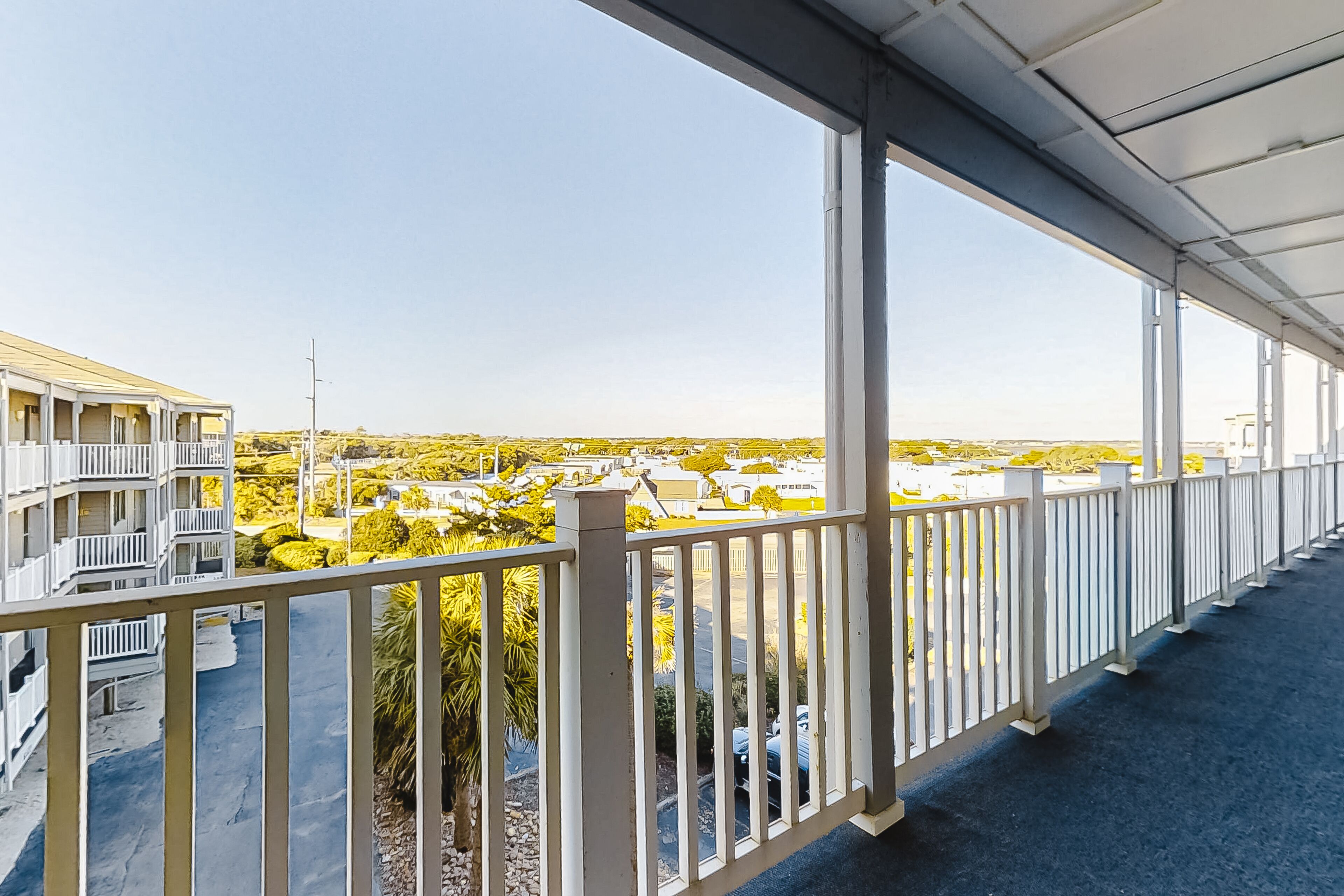 Un balcón con vistas a una zona residencial, con casas y vegetación.