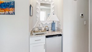Een badkamer met een witte wastafel, een decoratieve spiegel, een blauwe lamp en een schilderij aan de muur.