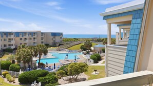 Un hotel con piscina, palmeras y vista al océano.