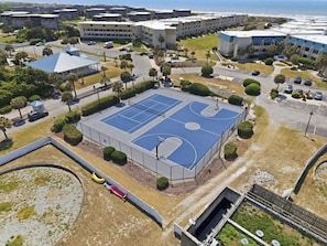 Vista aérea de un complejo deportivo con cancha de baloncesto, rodeado de edificios y un estacionamiento.