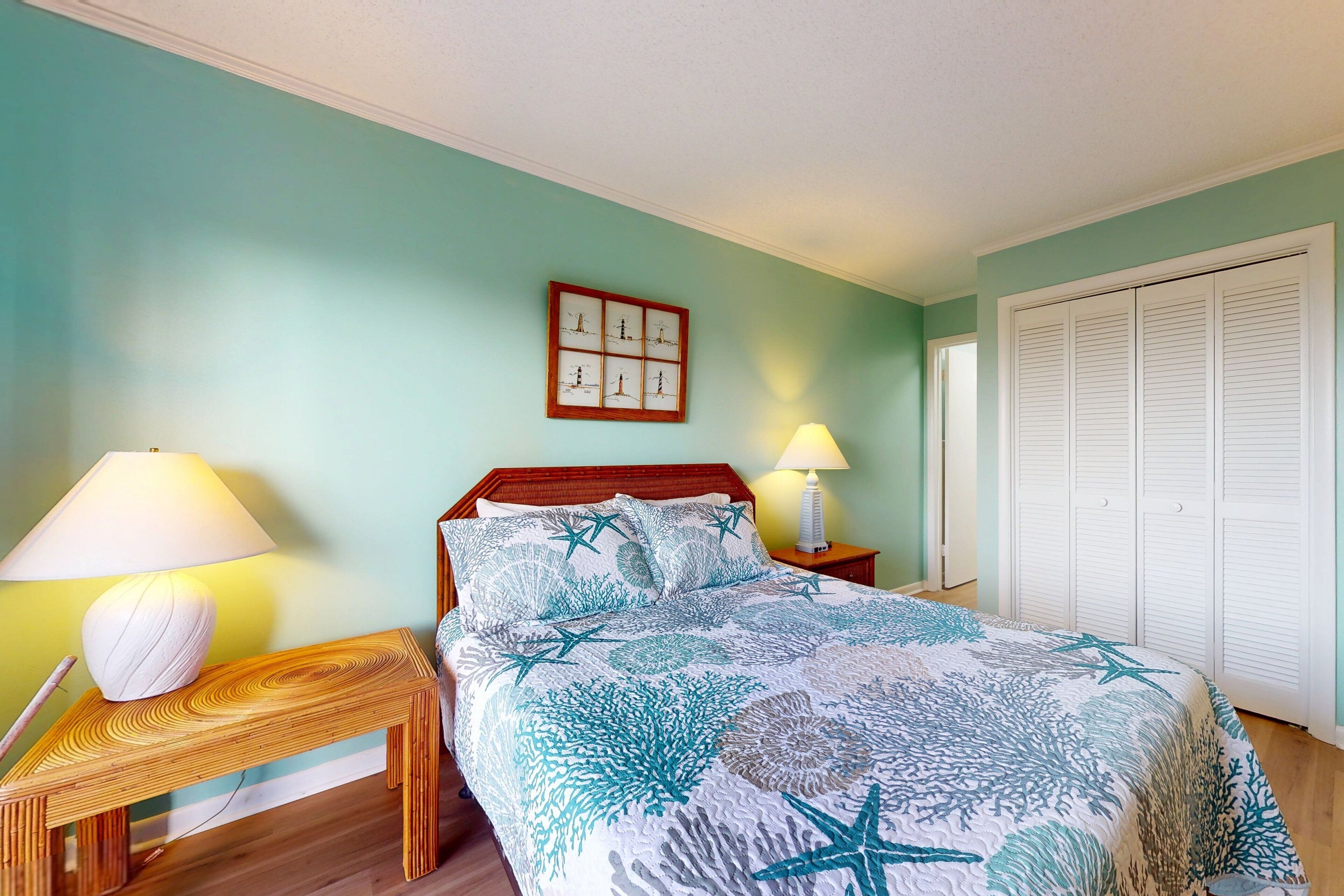 Une chambre à coucher comprenant un lit, deux tables de chevet, une commode, un tableau accroché au mur et un placard.