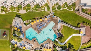 Eine Vogelperspektive eines Resorts mit großem Pool, Liegestühlen und einer Rutsche.