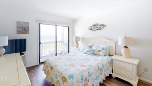 Une chambre à coucher avec un lit, des tables de chevet, une télévision et un balcon.