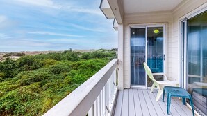 Ein Balkon mit Blick auf grüne Vegetation und einen klaren Himmel.