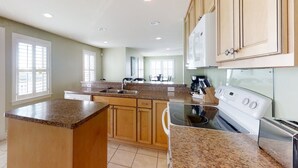 A kitchen with granite countertops, wooden cabinets, a built-in oven, and a sink. - Kellum Cottage: Spacious oceanfront home, large deck, beach access (Atlantic Beach)