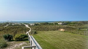 A pathway leading to a grassy area with a bench and a fence. - Kellum Cottage: Spacious oceanfront home, large deck, beach access (Atlantic Beach)