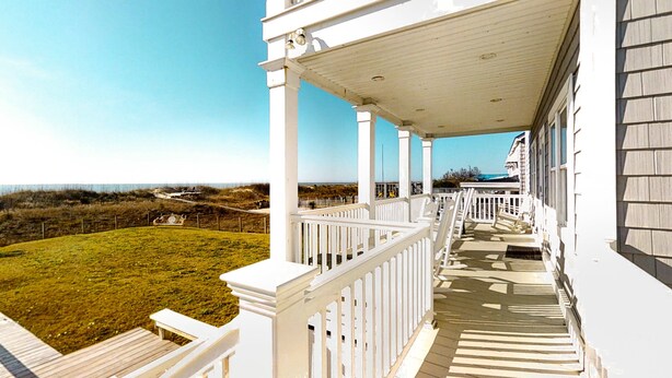 A white building with a covered porch and a grassy yard. - Kellum Cottage: Spacious oceanfront home, large deck, beach access (Atlantic Beach)