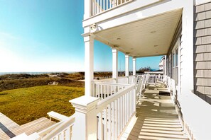 A white building with a covered porch and a grassy yard. - Kellum Cottage: Spacious oceanfront home, large deck, beach access (Atlantic Beach)