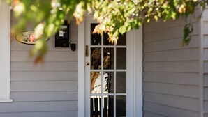 A white wooden door with a glass panel, a mailbox, and a small sign above the door. - Pear Tree Cottage - Apollo Bay (Apollo Bay)