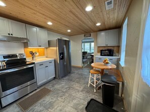 A modern kitchen with stainless steel appliances, wooden cabinets, and a breakfast bar. - Cozy Relaxing Getaway ~ Private Yard ~ Smart TV ~ Family Friendly (Seville)