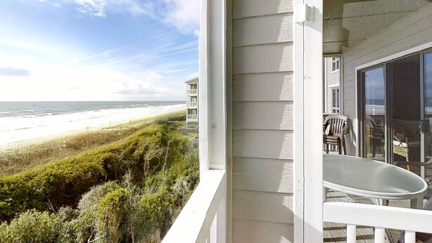 A balcony with a view of the beach and ocean.
