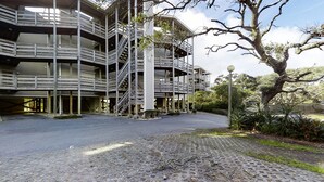 A multi-story building with a central staircase, surrounded by a paved area and greenery.
