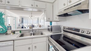 A modern kitchen with stainless steel appliances, white cabinetry, and a built-in oven.