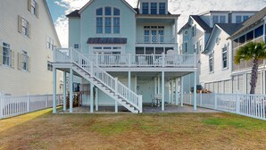 A two-story house with a balcony, a staircase, and a fenced yard. - Soundside Serenity: Perfect Beach Getaway with Water Views, Shared Pool (Atlantic Beach)