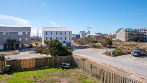A residential area with a white building, a stop sign, and a car parked on the street. - The Willis: Dog Friendly, Ocean/Sound View Condo, Near Beach (Atlantic Beach)