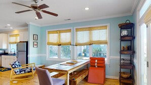 A spacious kitchen with wooden flooring, a dining table, and a ceiling fan. - The Willis: Dog Friendly, Ocean/Sound View Condo, Near Beach (Atlantic Beach)