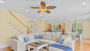 A spacious living room with a large sectional sofa, a wooden coffee table, and a ceiling fan. - Dog-friendly home with ocean/sound views and private beach path (Pine Knoll Shores)