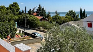 Et boligområde med udsigt over havet, huse med røde tage, og en parkeret bil.