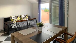 En moderne stue med sofa, spisebord og udsigt til det fri.