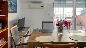 Un coin repas avec une table en bois, des chaises et un téléviseur posé sur un meuble.