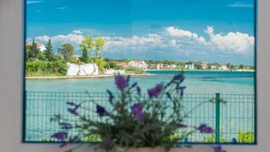 A coastal view with a clear sky, a body of water, and a fence with purple flowers in the foreground. - Lovely home in Privlaka (Privlaka)