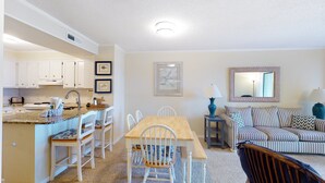 A compact living space with a kitchen, dining area, and seating area. - 2nd-Floor Condo in Oceanfront Location w/WiFi, Screened-In Balcony, Shared Pool (Atlantic Beach)